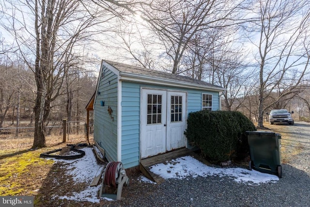 view of outdoor structure featuring fence and an outbuilding