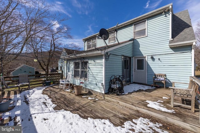 snow covered property featuring a shingled roof and a wooden deck