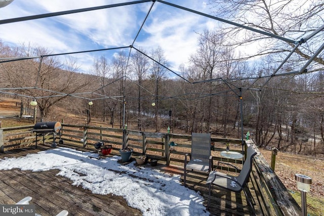 snow covered patio featuring grilling area and a deck