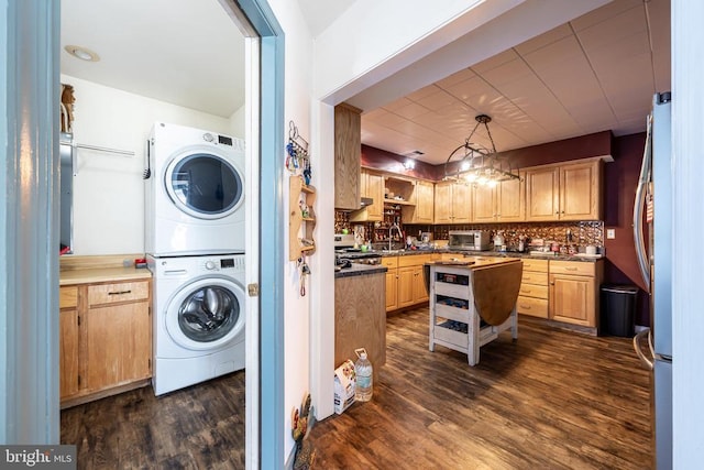 laundry area featuring dark wood-style floors, stacked washer / dryer, a toaster, and a sink