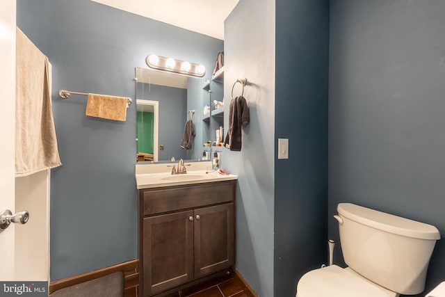 bathroom featuring baseboards, vanity, and toilet