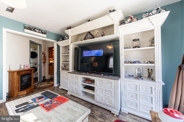 living room featuring dark wood-style flooring and stacked washer / drying machine