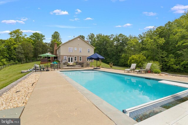 outdoor pool with a patio, a lawn, and a diving board