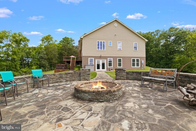view of patio featuring a fire pit, view of scattered trees, a wooden deck, and french doors