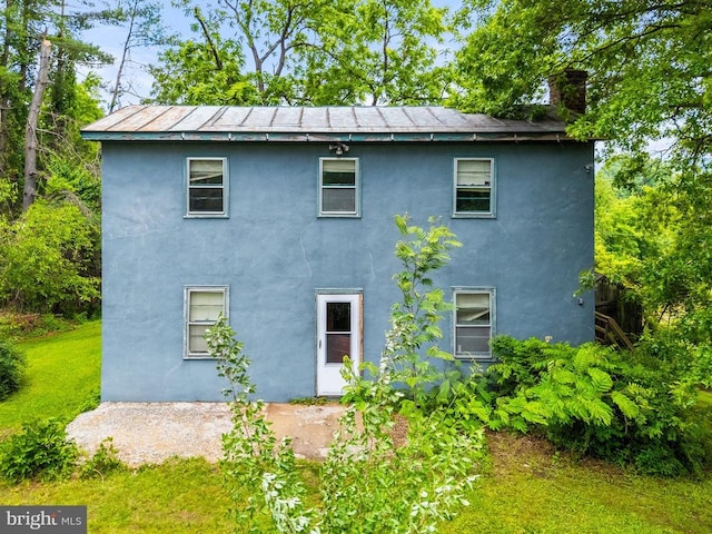  - view of property exterior with stucco siding, a chimney, and a lawn