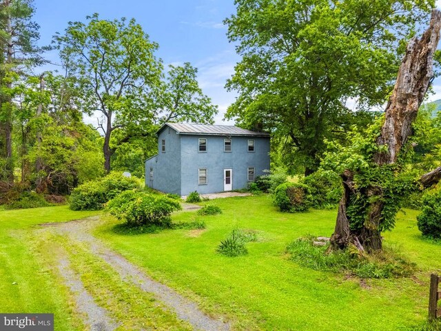  - view of home's exterior featuring stucco siding, a standing seam roof, dirt driveway, and a yard