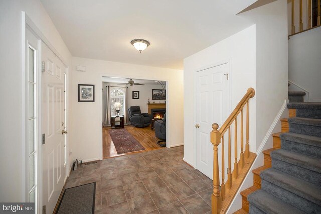 6117 Block House Rd, Partlow, VA 22534 - entrance foyer with stairs, a ceiling fan, a lit fireplace, and baseboards