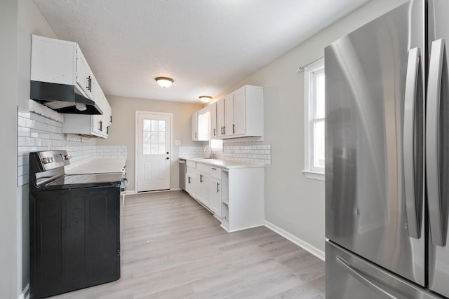129 Hillwood Dr, Front Royal, VA 22630 - kitchen with appliances with stainless steel finishes, under cabinet range hood, light countertops, backsplash, and light wood-type flooring