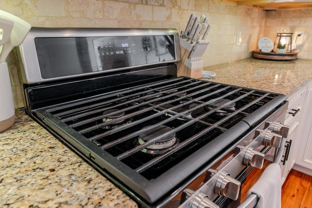 731 Hidden Brook Rd, Mcgaheysville, VA 22840 - kitchen view of stainless steel range with gas cooktop, white cabinets, decorative backsplash, and light stone counters