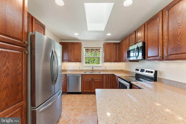  - kitchen featuring appliances with stainless steel finishes, recessed lighting, a skylight, light tile patterned flooring, and brown cabinetry