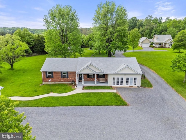  - single story home featuring covered porch, brick siding, a front yard, and gravel driveway