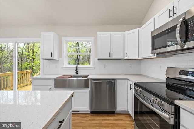 358 Hemlock Ln, Mineral, VA 23117 - kitchen with appliances with stainless steel finishes, plenty of natural light, backsplash, white cabinetry, and lofted ceiling