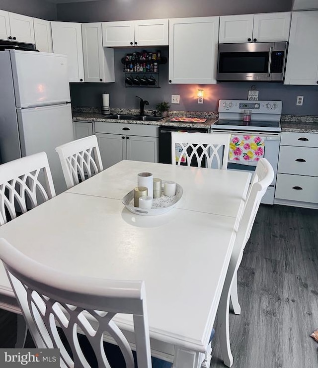 5122 Cottonwood Ct, Fredericksburg, VA 22407 - kitchen featuring white appliances, dark wood-type flooring, white cabinetry, and a kitchen breakfast bar