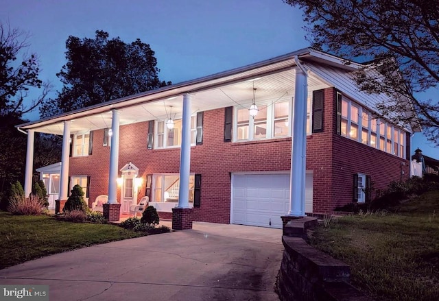 neoclassical / greek revival house featuring an attached garage, concrete driveway, a porch, and brick siding