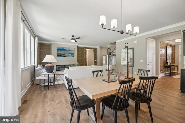  - dining space with crown molding, wood finished floors, a ceiling fan, a chandelier, and baseboards