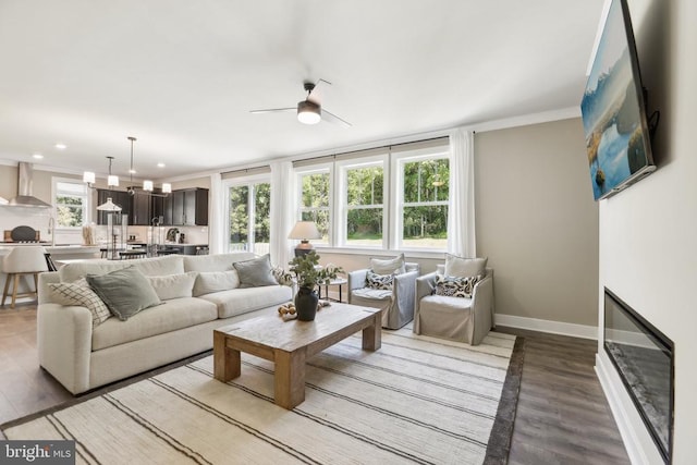  - living area with a ceiling fan, wood finished floors, crown molding, recessed lighting, and baseboards