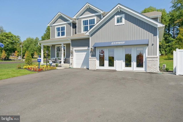  - view of front of home featuring driveway, covered porch, french doors, and an attached garage