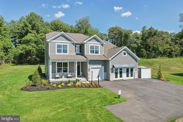  - craftsman-style house featuring covered porch, asphalt driveway, a front yard, and board and batten siding