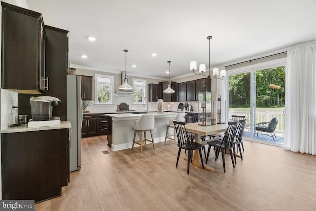  - dining area with light wood-style floors, ornamental molding, a chandelier, and recessed lighting