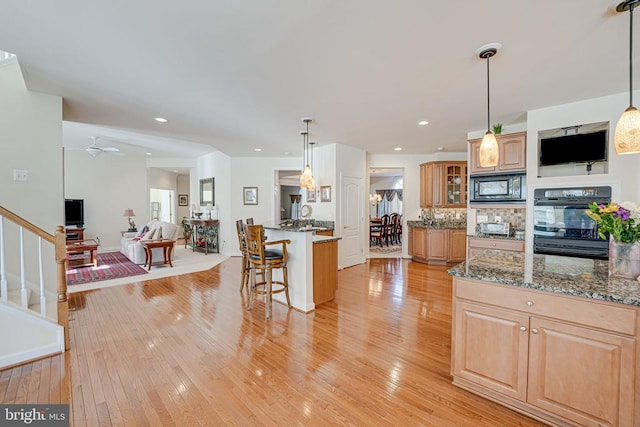 11512 Balmartin Ct, Spotsylvania, VA 22553 - kitchen featuring black appliances, a breakfast bar, open floor plan, light wood finished floors, and dark stone counters