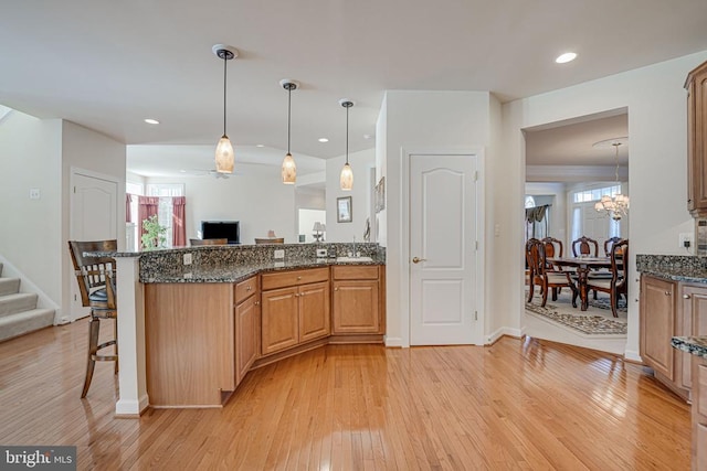 11512 Balmartin Ct, Spotsylvania, VA 22553 - kitchen with light wood-style flooring, dark stone countertops, a kitchen breakfast bar, pendant lighting, and recessed lighting