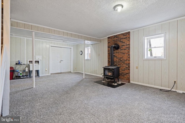 9128 Woodbrook Ln, Culpeper, VA 22701 - below grade area featuring a wood stove, ornamental molding, a textured ceiling, carpet floors, and wood walls