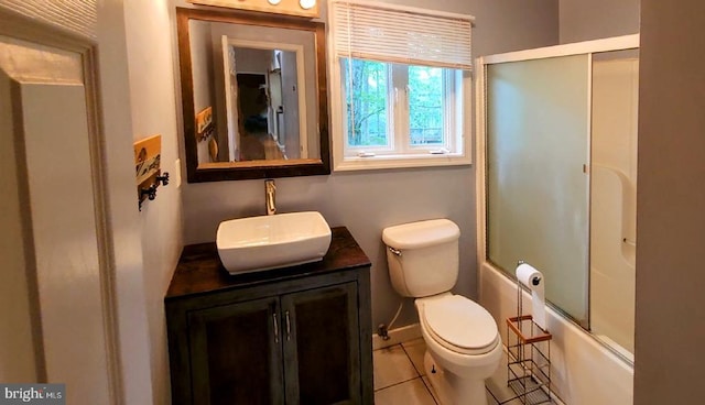 bathroom featuring toilet, vanity, tile patterned floors, and bath / shower combo with glass door