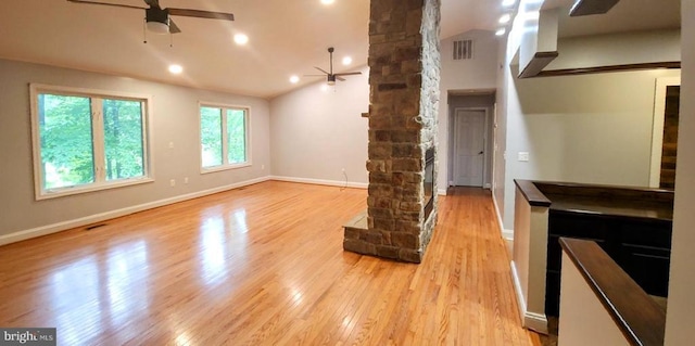 unfurnished living room featuring a ceiling fan, ornate columns, light wood finished floors, lofted ceiling, and baseboards