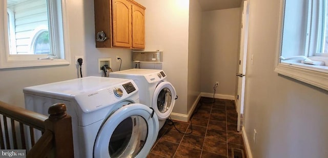 laundry area featuring cabinet space, washing machine and dryer, healthy amount of natural light, and baseboards