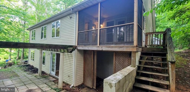 rear view of house with a sunroom, stairway, and a deck