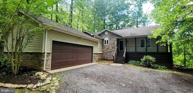 ranch-style home featuring stone siding, covered porch, driveway, and roof with shingles