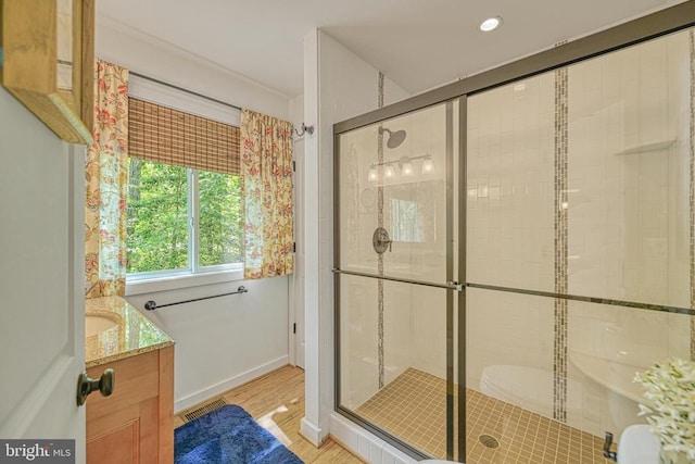 bathroom featuring a shower stall, wood finished floors, vanity, and baseboards