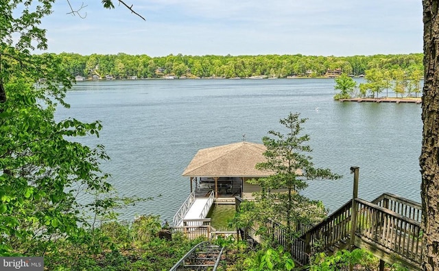 water view with stairway and a heavily wooded area
