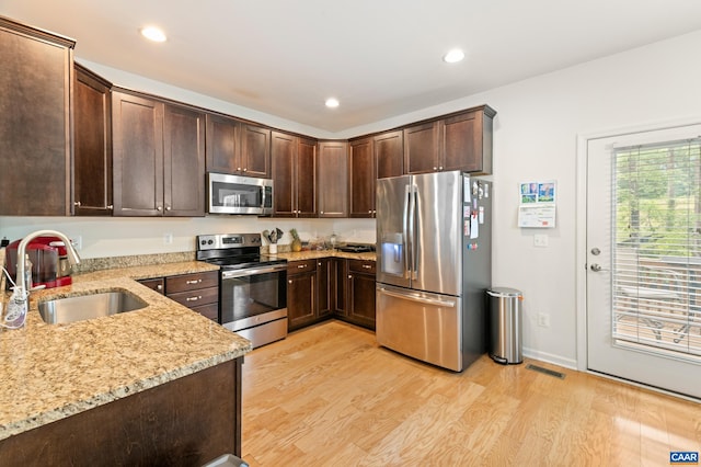 139 Longwood Dr, Charlottesville, VA 22903 - kitchen with stainless steel appliances, a sink, dark brown cabinets, light wood-style flooring, and light stone counters