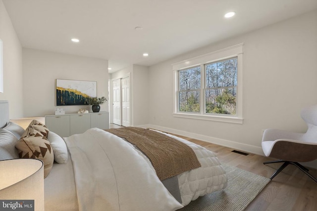 bedroom with a closet, visible vents, recessed lighting, and light wood-style floors