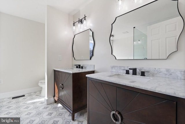 full bathroom featuring visible vents, toilet, two vanities, a sink, and baseboards