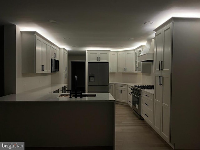 kitchen featuring a sink, black fridge with ice dispenser, a peninsula, stainless steel stove, and custom exhaust hood