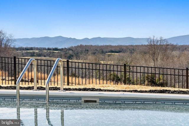 view of swimming pool featuring a mountain view and fence