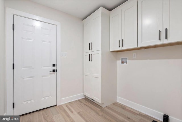 washroom featuring light wood finished floors, hookup for a washing machine, cabinet space, and baseboards