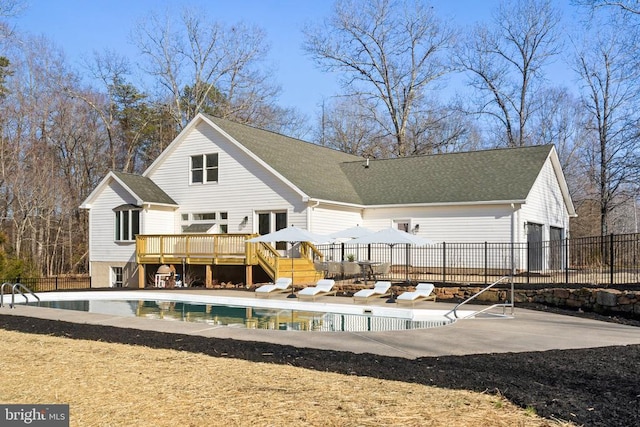 rear view of house with a patio, fence, a fenced in pool, roof with shingles, and a deck