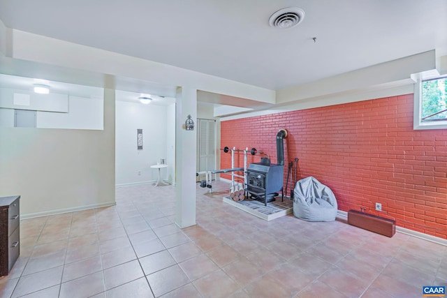 711 Jefferson Dr, Palmyra, VA 22963 - living area featuring brick wall, a wood stove, light tile patterned floors, and baseboards