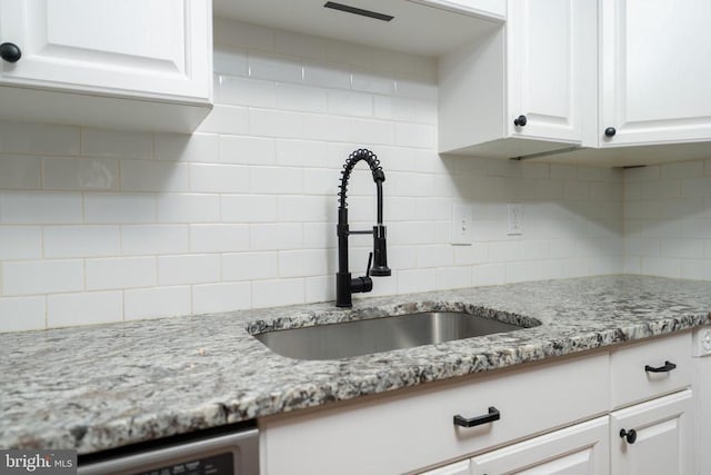 - interior details featuring beverage cooler, a sink, white cabinets, light stone countertops, and tasteful backsplash