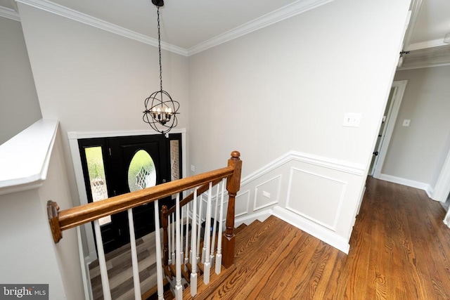  - stairway featuring an inviting chandelier, wood finished floors, a wainscoted wall, and ornamental molding