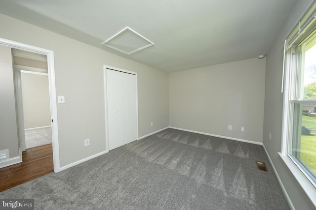  - unfurnished bedroom with a closet, attic access, baseboards, visible vents, and dark carpet