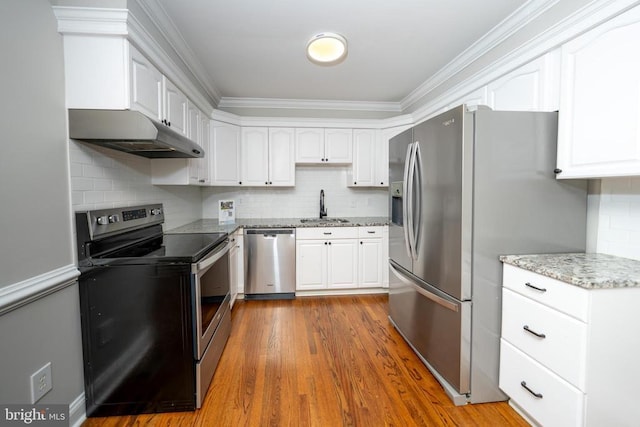 - kitchen with a sink, stainless steel appliances, ornamental molding, under cabinet range hood, and light stone countertops