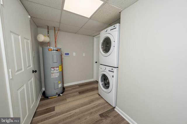  - clothes washing area featuring light wood finished floors, stacked washer / drying machine, laundry area, baseboards, and electric water heater