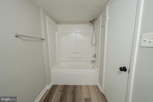  - bathroom with wood finished floors, baseboards, and washtub / shower combination