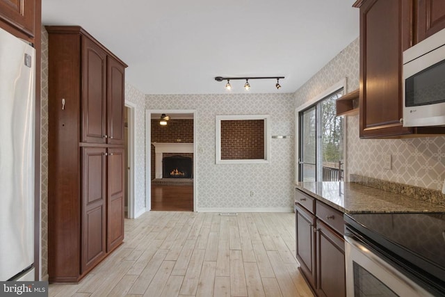 9 Twin Springs Dr, Fredericksburg, VA 22407 - kitchen featuring stainless steel appliances, light wood-style flooring, dark stone counters, open shelves, and a brick fireplace