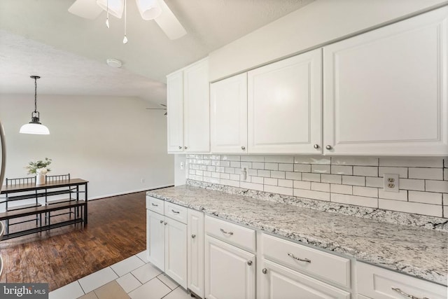  - kitchen featuring a ceiling fan, white cabinets, vaulted ceiling, decorative backsplash, and hanging light fixtures