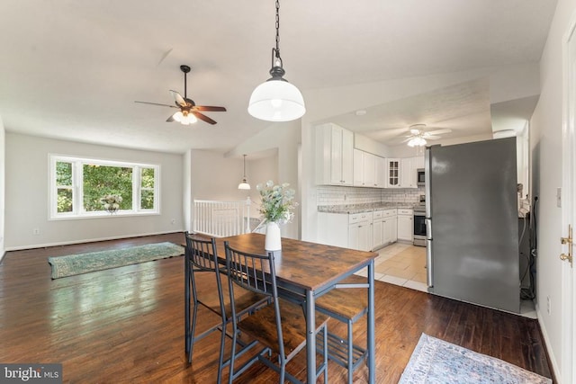  - dining room with ceiling fan, vaulted ceiling, and wood finished floors